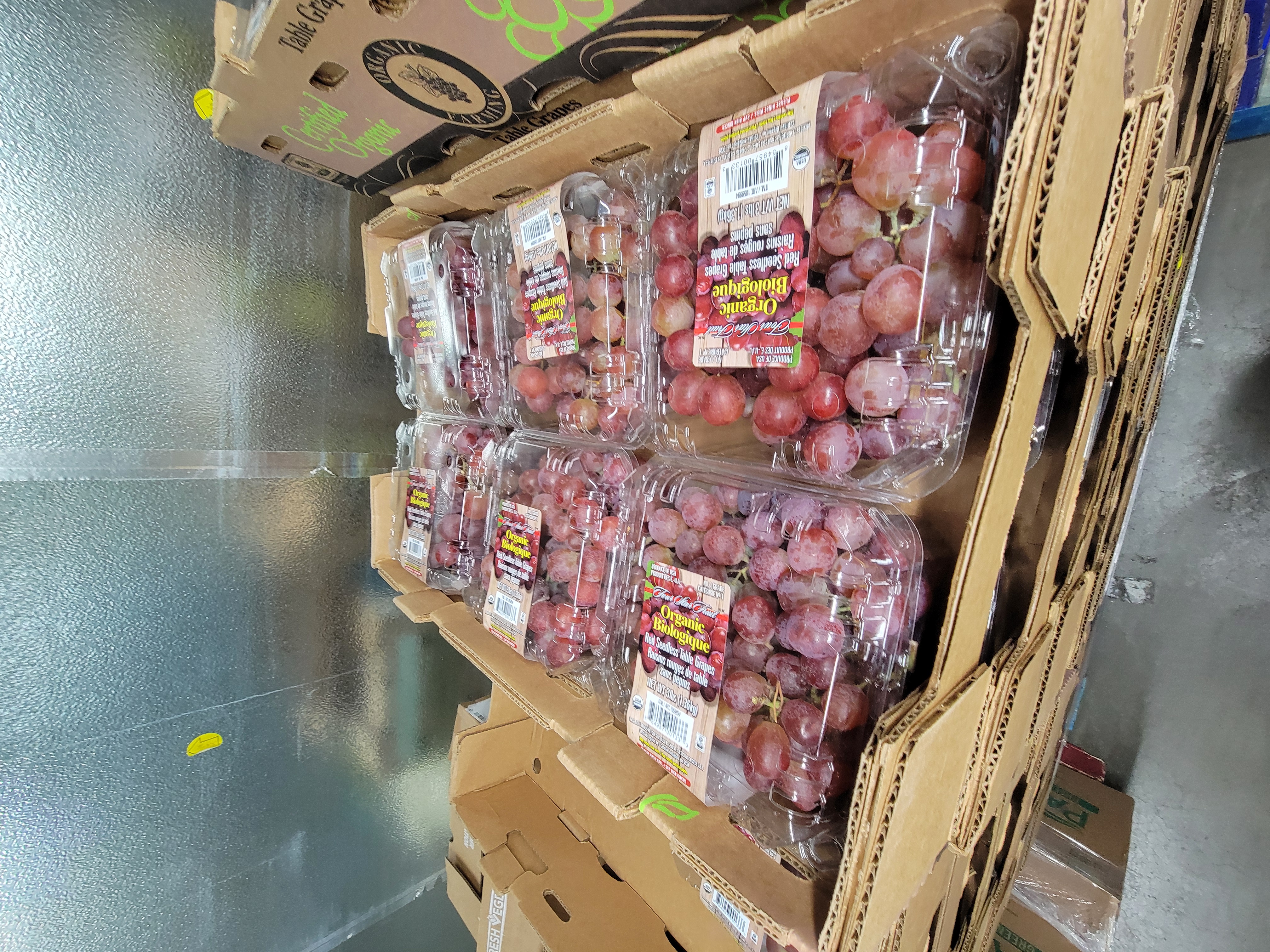 Fruit box filled with clam shell containers of red grapes.